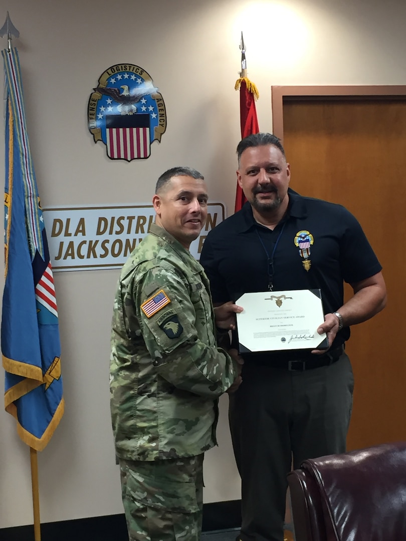DLA Distribution commanding general, U.S. Army Brig. Gen. John S. Laskodi (left) presents Brian Burkholder the DLA Superior Civilian Service Award for his achievements while serving as director, Defense Logistics Agency Distribution Jacksonville, Florida, from August 2014 to August 2017.