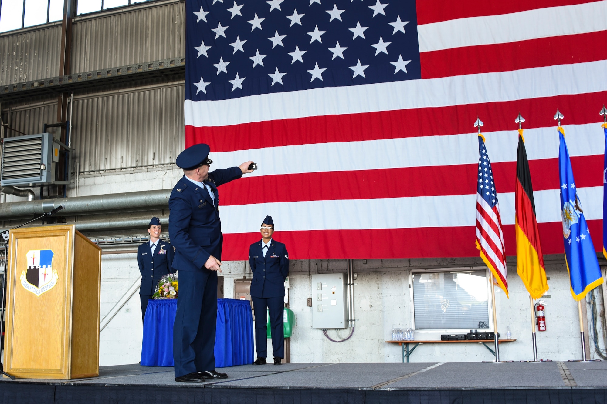 U.S. Air Force Col. Joseph McFall, outgoing 52nd Fighter Wing commander, takes a selfie before relinquishing command to Col. Jason Bailey, incoming commander, during the wing change of command ceremony in Hangar 1 at Spangdahlem Air Base, Germany, Aug. 29, 2017.  Nearly 400 people attended the event to witness the traditional change of command ceremony as Bailey accepted responsibility as the wing commander. (U.S. Air Force photo b Senior Airman Dawn M. Weber)