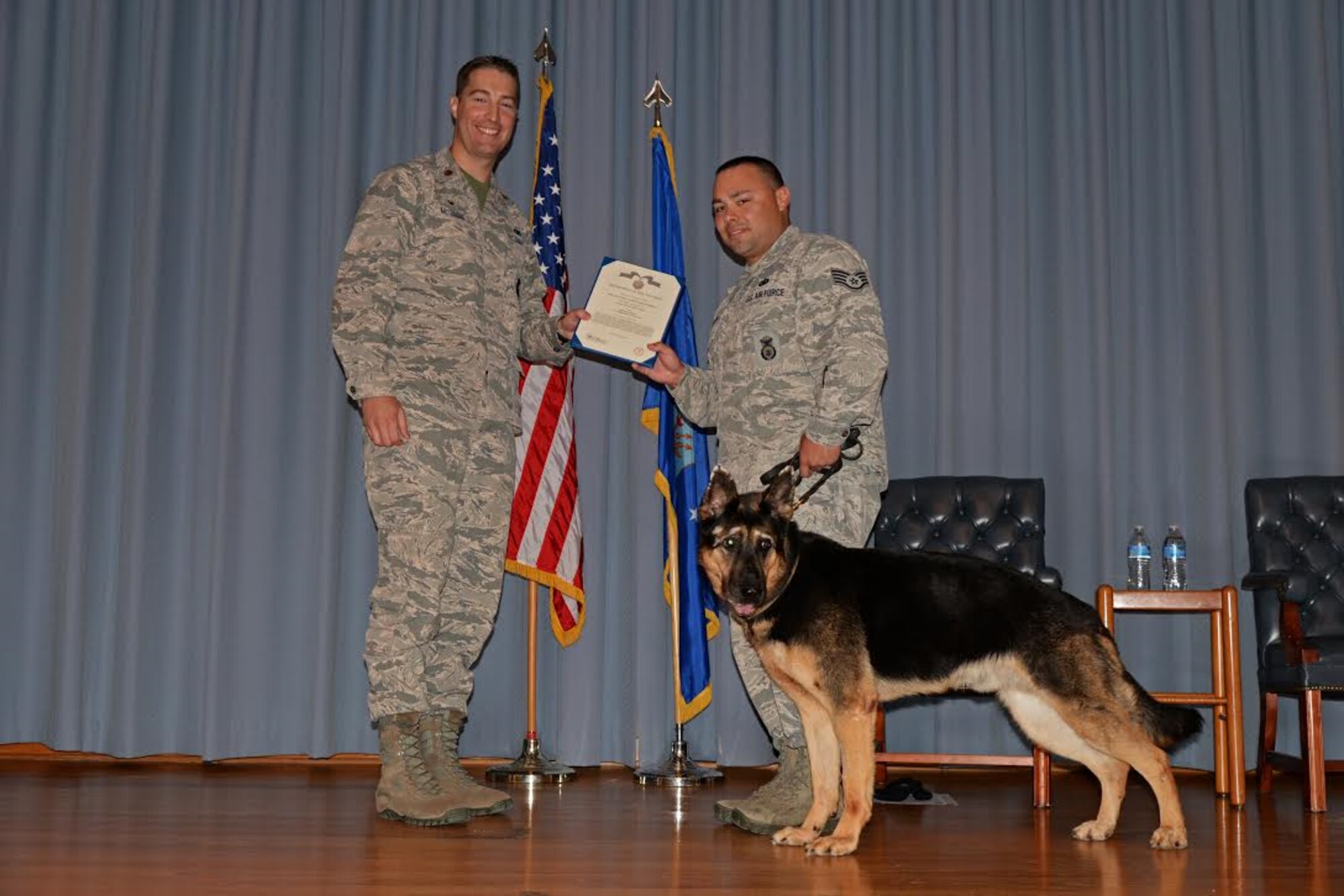 U.S. Air Force Maj. Matthew McGinnis, 47th Security Forces Squadron commander, presents an award to Staff Sgt. Cody Davidson, 47th Military Working Dogs patrolman, and his K-9 dog Foxo, during a retirement ceremony for Foxo at Laughlin Air Force base, Texas on August 25, 2017.