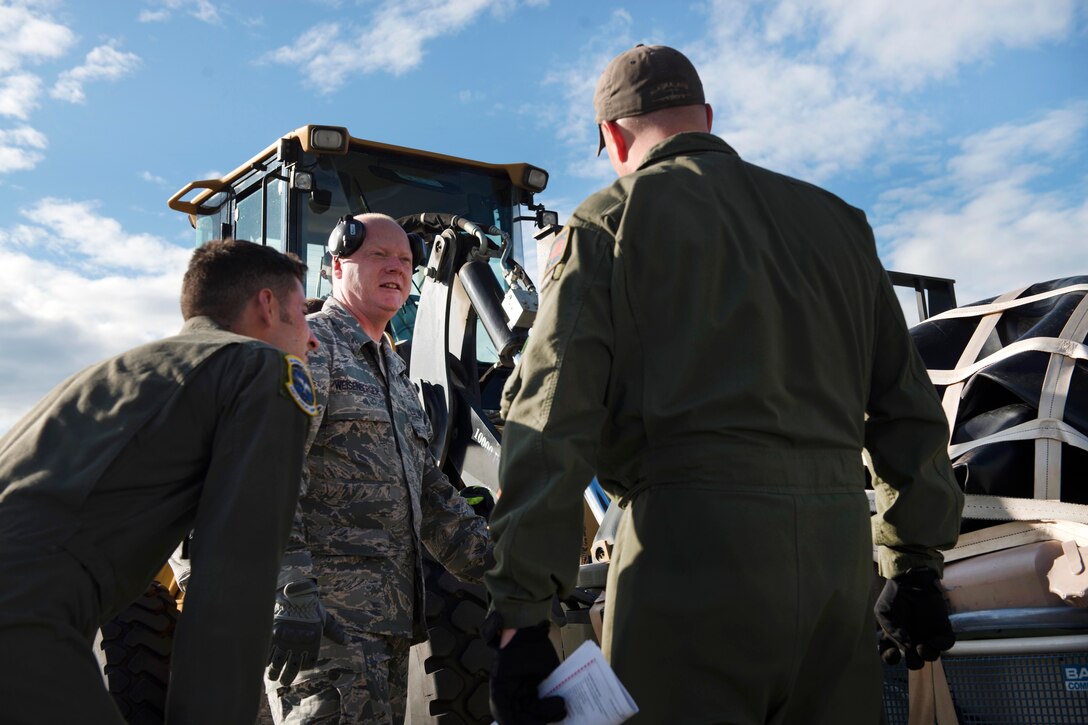 Airmen load and secure cargo onto large machinery.