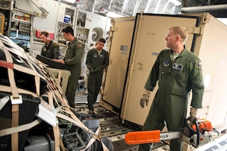 A group of Airmen load equipment in the cargo hold of an airplane.