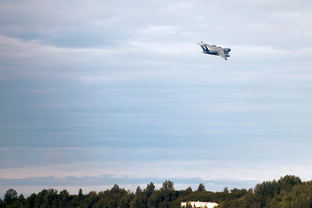 An airplane flies in overcast skies.