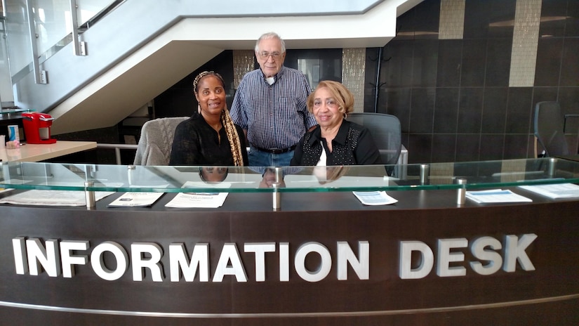 Ms. Marjorie Dixson, left, Mr. Ron Liljedahl, center, and Ms. Bettye Wray are volunteers at Malcolm Grow Medical Clinic and Surgery Center.  They work at the main information desk in building 1060, helping to direct patients to clinics and answering questions.