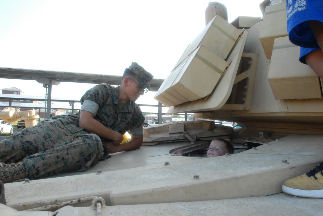 A Marine is ready to assist a young boy out of the Assault Breacher Vehicle (ABV) as part of the Static Display portion of MCES' Kids Rock Day on August 18, 2017.