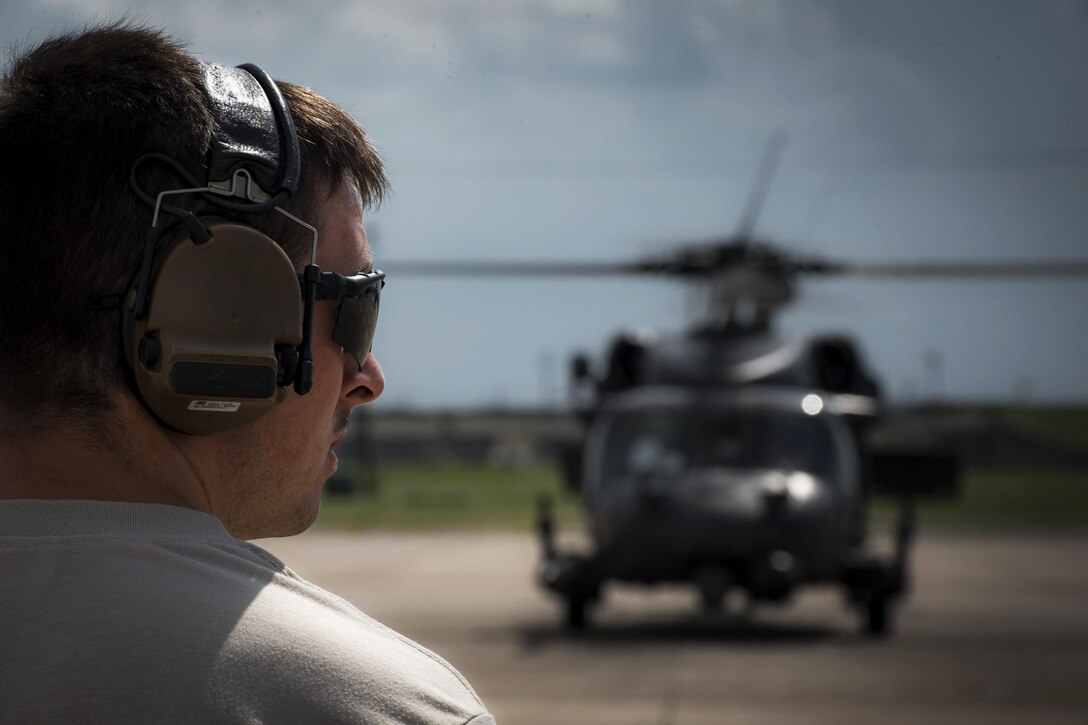 An airman watches a helicopter.