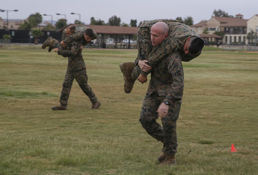 Marines with Headquarters and Headquarters Squadron (H&HS) fireman carry simulated casualties during the maneuver under fire potion of the Warrior Challenge at Marine Corps Air Station Miramar, Calif., Aug 22.  This monthly challenge gives sections within H&HS the opportunity to work as a team and compete in several training events. (U.S. Marine Corps photo by Cpl. Andrianna Talbot/Released)