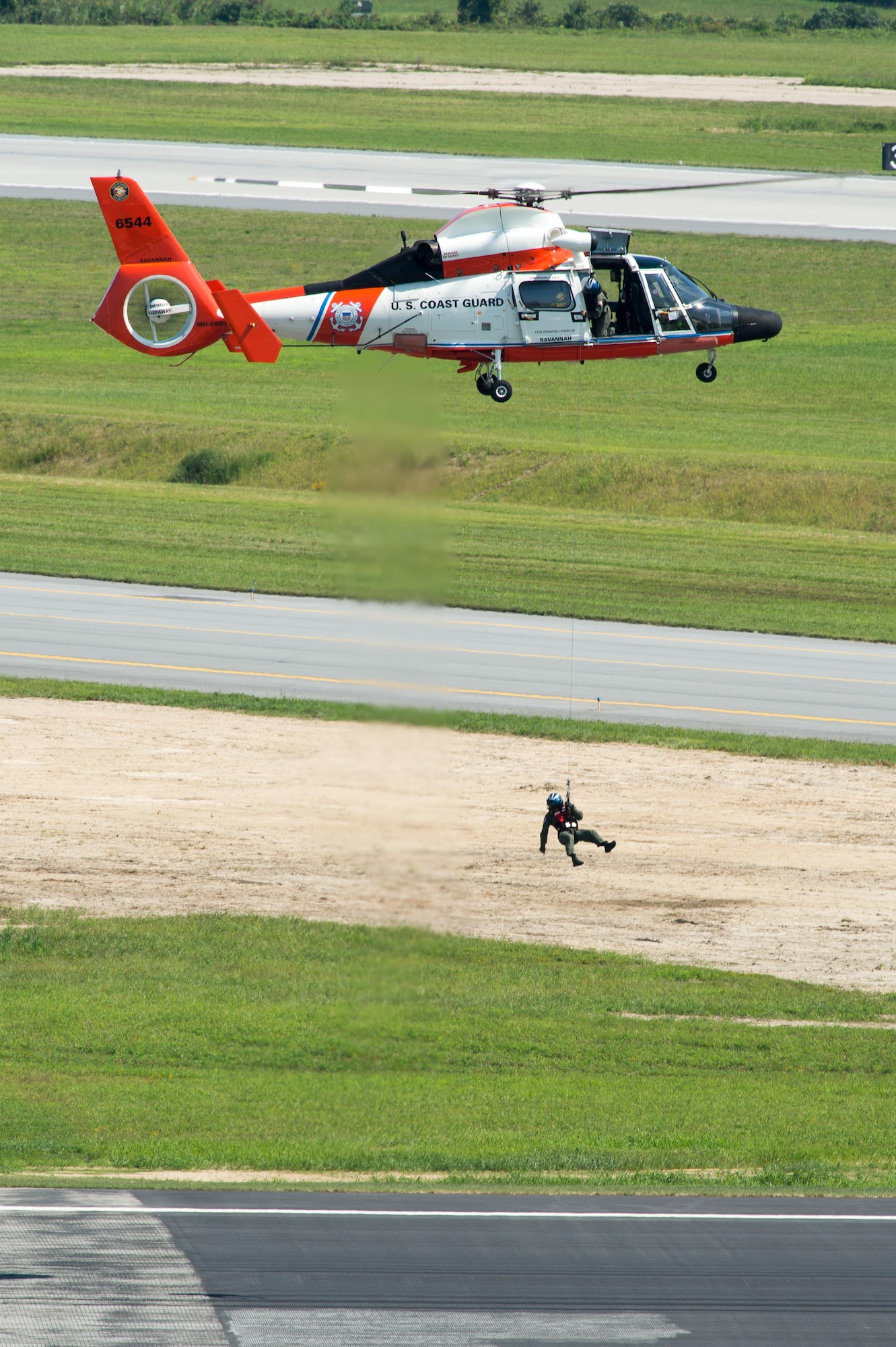 The crew of a U.S. Coast Guard MH-65D Dolphin helicopter performs a search and rescue demonstration at the Thunder Over Dover Open House and Airshow Aug. 26, 2017, at Dover Air Force Base, Del. The open house was a free, two-day event that featured more than 20 aerial demonstrations, static aircraft displays, and other events. (U.S. Air Force photo by Mauricio Campino)