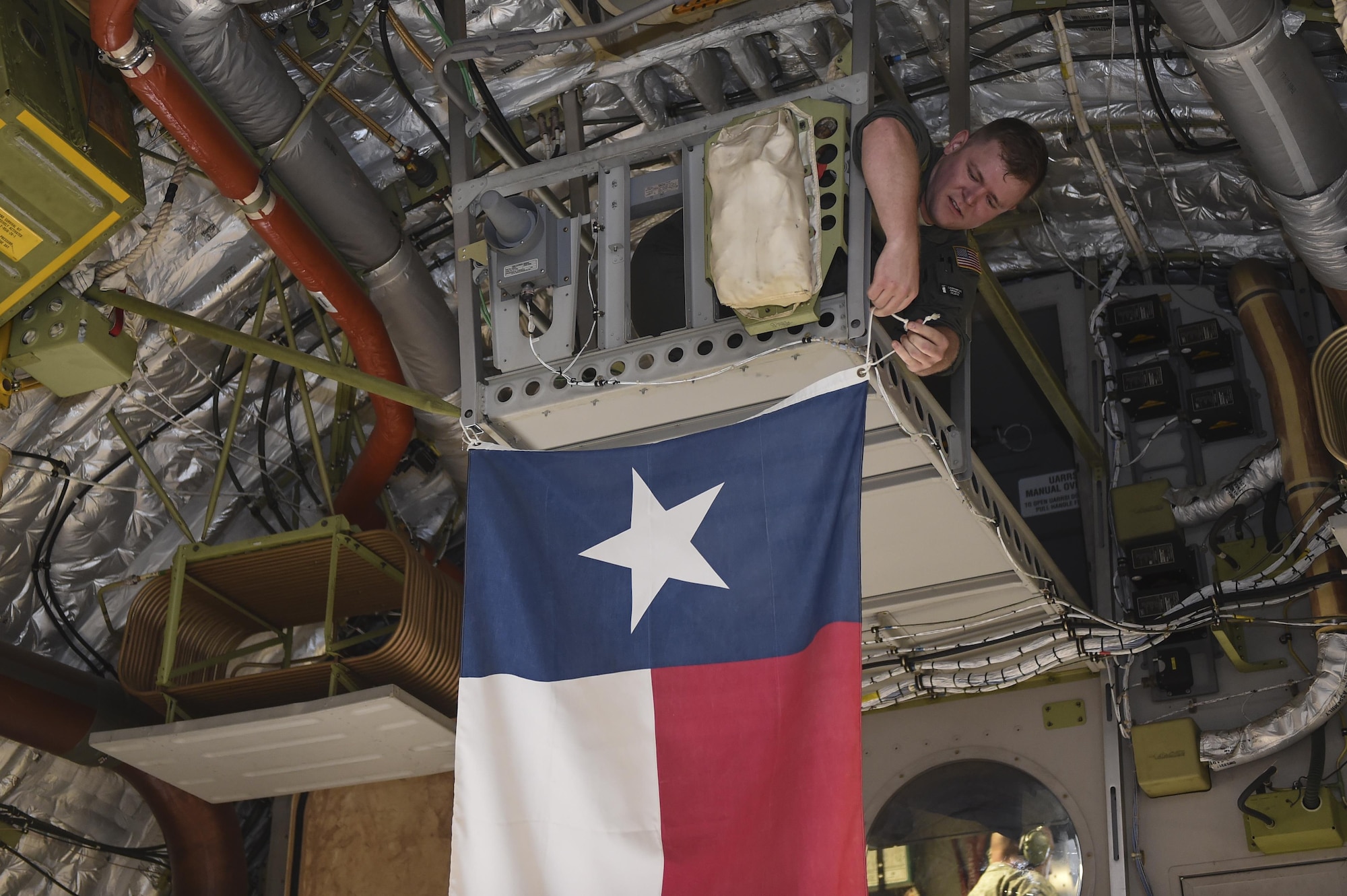 Senior Airman Justin Hampton, 16th Airlift Squadron loadmaster, hangs the state flag of Texas prior to takeoff of a disaster relief mission Aug. 29.