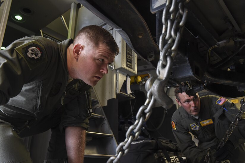 Senior Airman Justin Hampton, left, and Tech. Sgt. Joe Joiner, 16th Airlift Squadron loadmasters, left, checks the winches holding down a vehicle during a cargo on load at Robins Air Force Base, Ga., flightline Aug. 29.