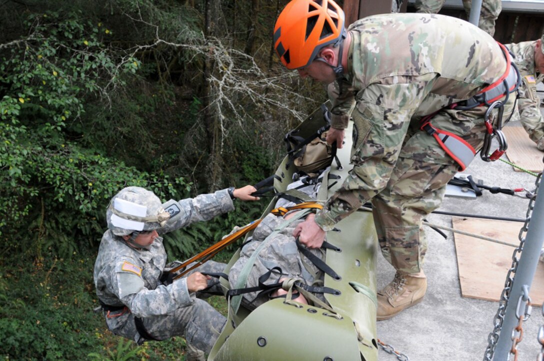 A soldier descends a wall with a simulated casualty.