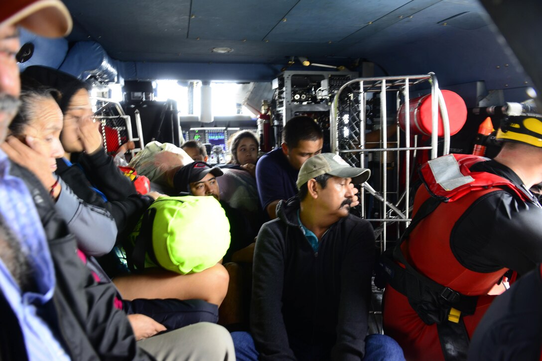 Members of the Coast Guard fly displaced residents in a MH-65 Dolphin helicopter to a collection point after conducting a search and rescue mission