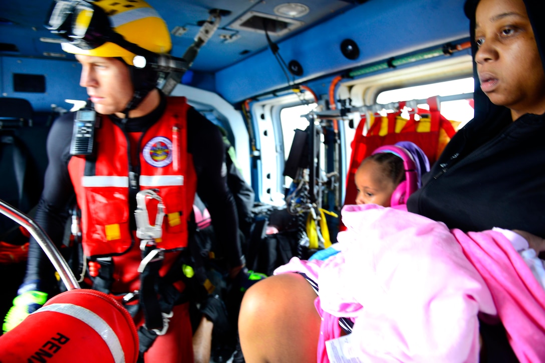 Members of the Coast Guard fly displaced residents in a MH-65 Dolphin helicopter to a collection point after conducting a search and rescue mission