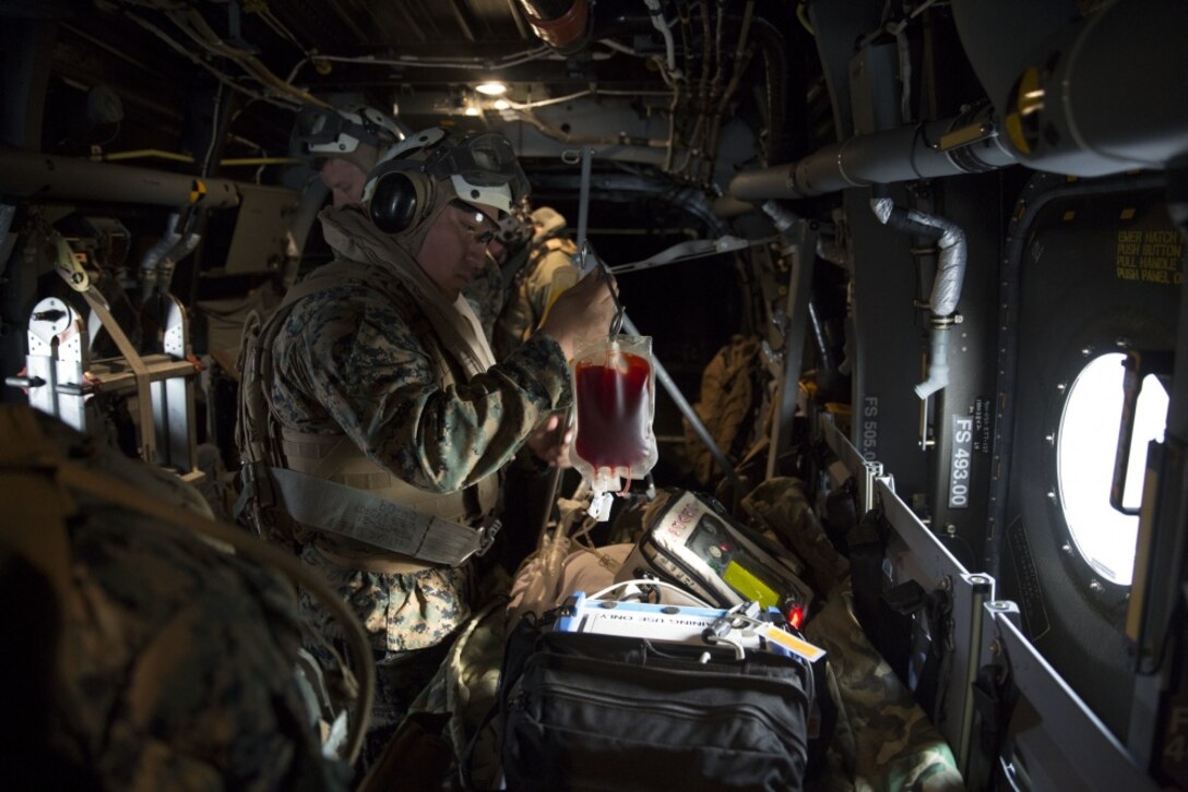 A corpsman inspects a blood bag for a simulated casualty during an en-route care training exercise for 2nd Medical Battalion at Camp Lejeune, N.C. on Aug 24, 2017. The training was conducted to prepare corpsmen to successfully aid casualties while transporting them via aircraft to a higher level of medical attention. The sailors are with 2nd Medical Battalion. (U.S. Marine Corps photo by Pvt. Nicholas Guevara)