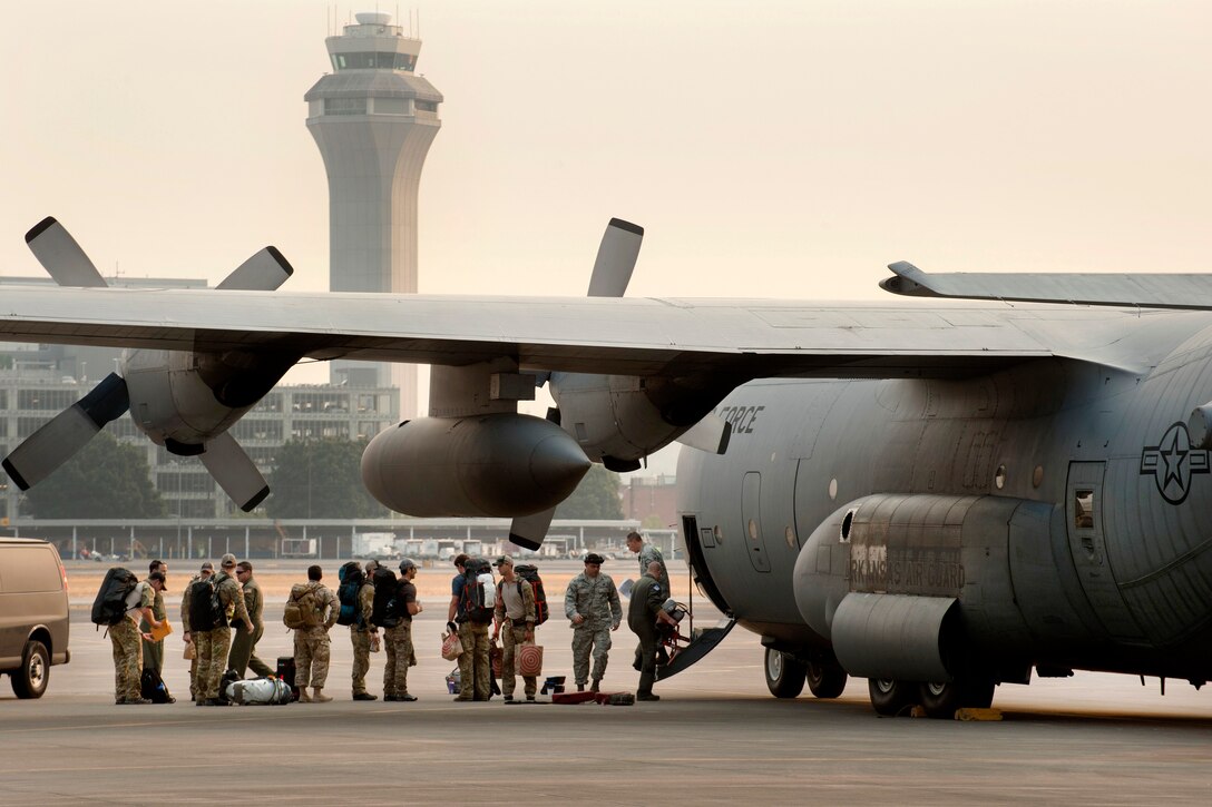 Airmen board an Air National Guard C-130 Hercules, as they prepare to depart the Portland Air National Guard Base