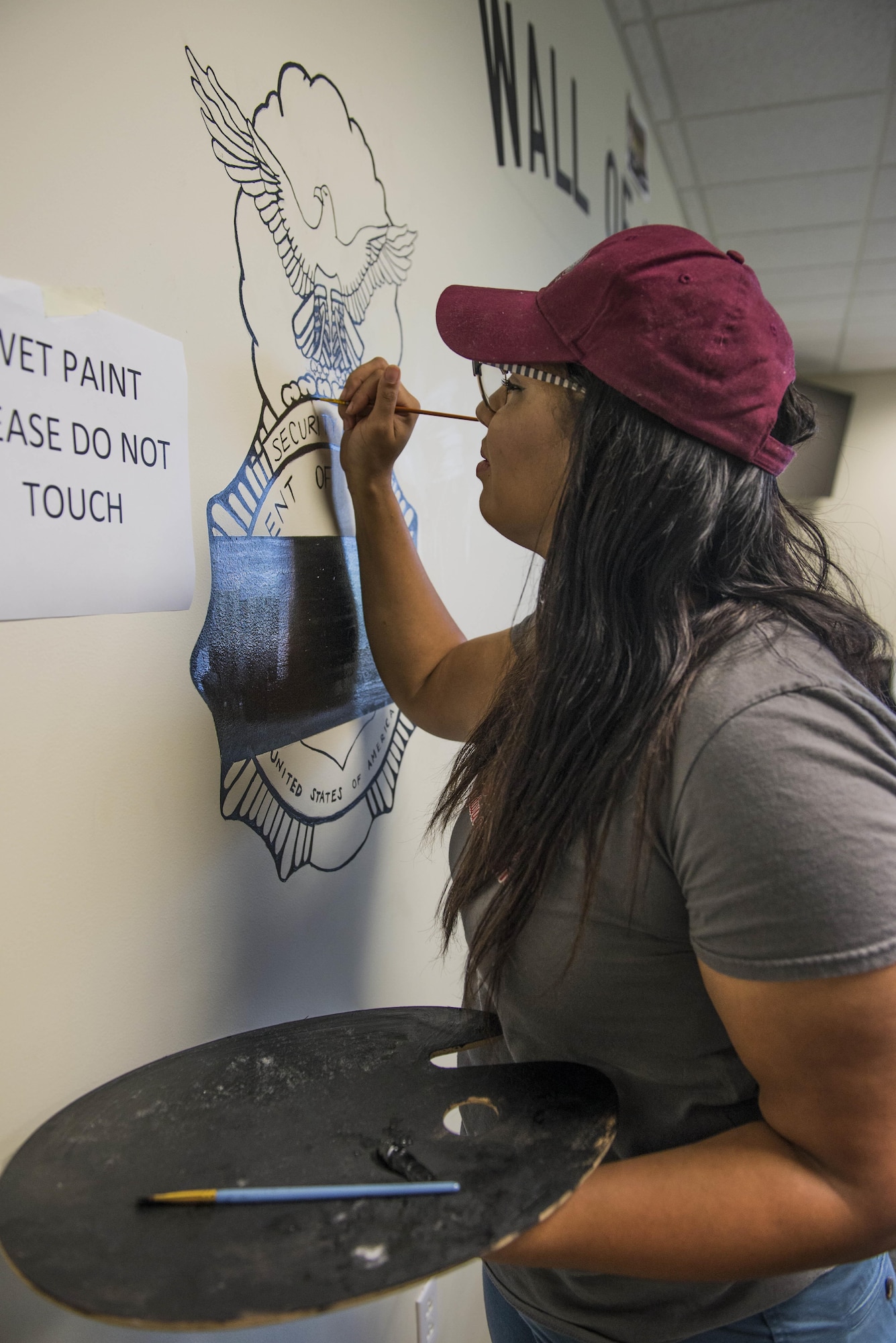 Lindenwood Belleville student Ginger Stockett, a criminal justice intern, paints a mural in the 375th Security Forces Squadron building at Scott.