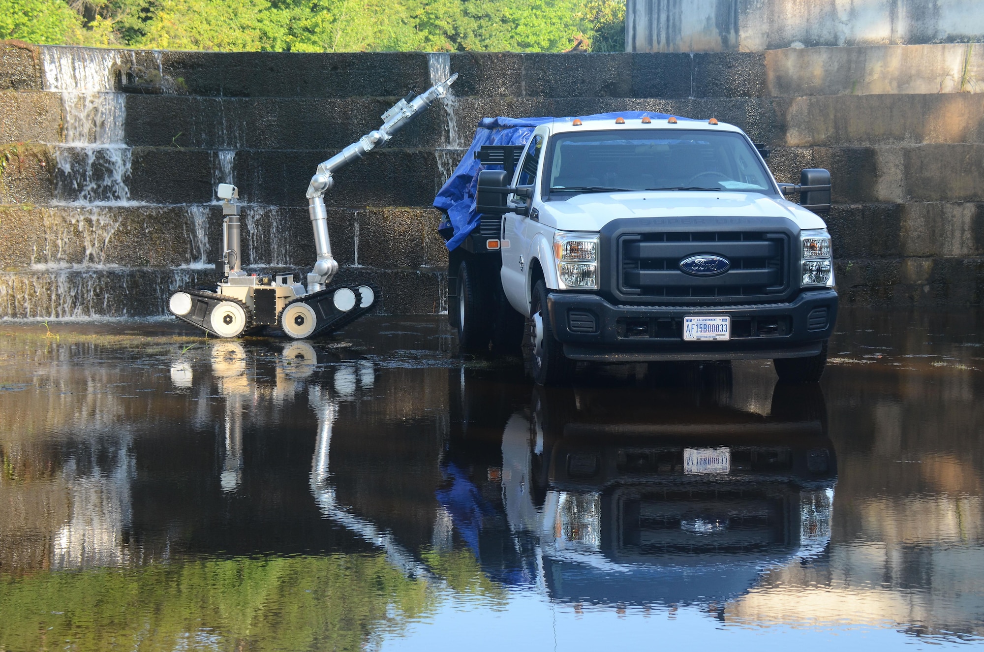 An explosive ordnance disposal robot pulls a tarp off barrels on the back of a truck during a simulated EOD training scenario at Dobbins Air Reserve Base, Ga. Aug. 22, 2017. The scenario was part of the second annual Eastern National Robot Rodeo. (U.S. Air Force photo/Don Peek)