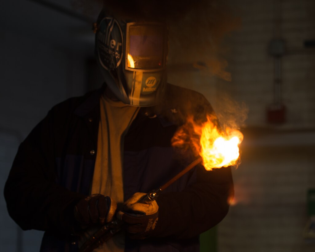 U.S. Air Force Airman 1st Class Jordan Mann, 1st Maintenance Squadron metals technology journeyman, lights a blow torch at the metals technology shop at Joint Base Langley-Eustis, Va., Aug. 17, 2017. The metal technicians use blow torches to melt and break down a piece of metal from equipment such as cargo crates. (U.S. Air Force photo by Senior Airman Derek Seifert)