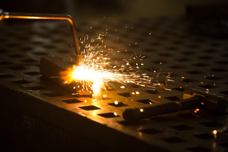 A blow torch burns a piece of metal at the metals technology shop at Joint Base Langley-Eustis, Va., Aug. 17, 2017. The 1st Maintenance Squadron metals technology shop supports the flightline and other units on JBLE that require specialized metal work. (U.S. Air Force photo by Senior Airman Derek Seifert)
