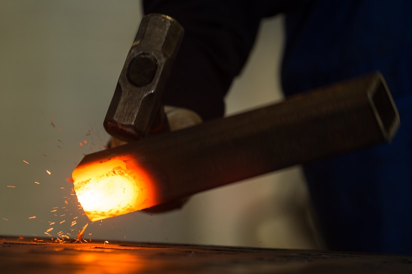A U.S. Air Force Airman strikes a burning piece of metal with a hammer to break it down at the metals technology shop at Joint Base Langley-Eustis, Va., Aug. 17, 2017. The main job of 1st Maintenance Squadron metal technology shop is to repair bushings, remove bolts and manufacture tools for crew chiefs and other shops across the installation. (U.S. Air Force photo by Senior Airman Derek Seifert)