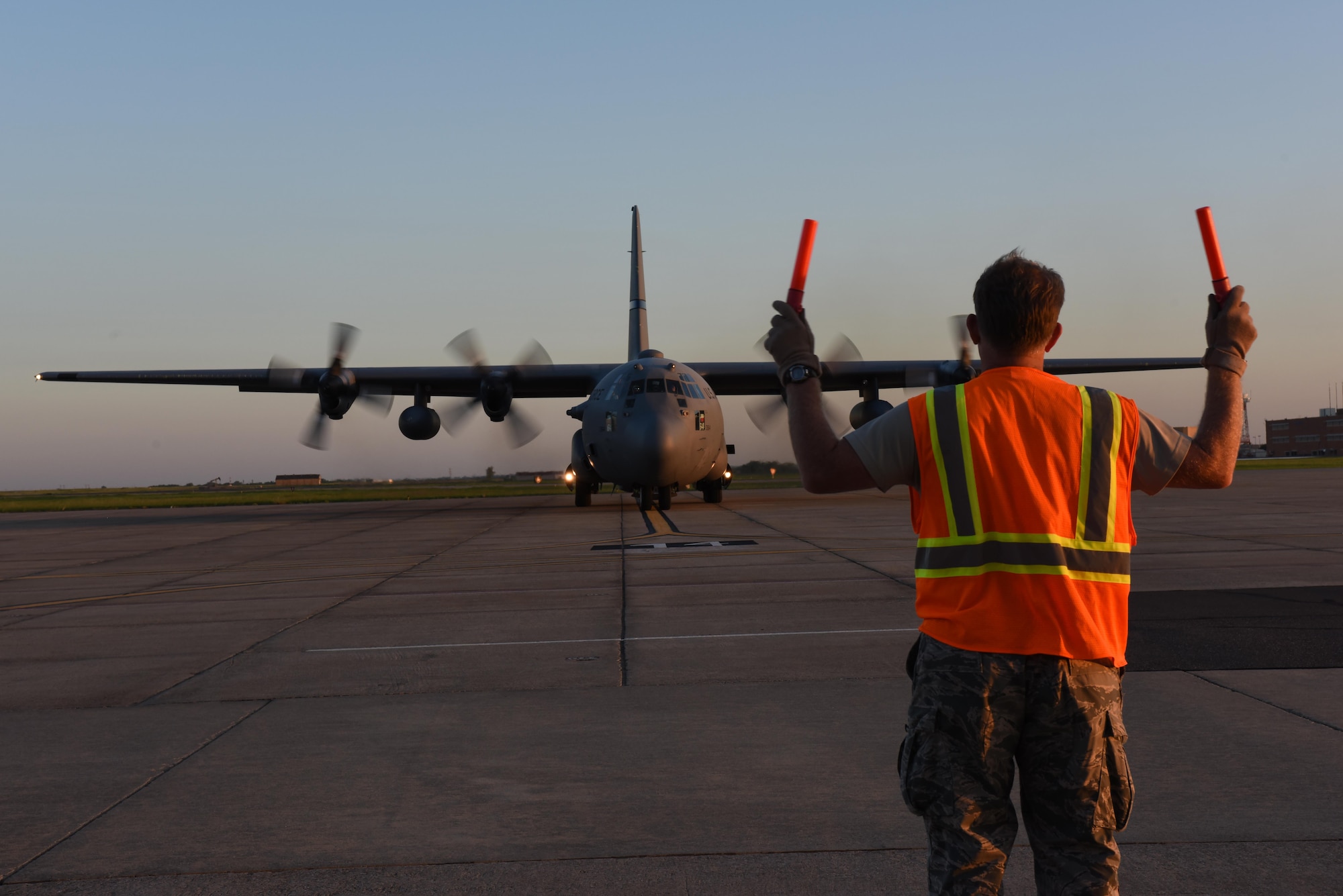An airfield manager from the 137th Special Operations Wing, Will Rogers Air National Guard Base in Oklahoma City, marshals a C-130 Hercules from the 136th Airlift Wing, Naval Air Station Fort Worth Joint Reserve Base at Carswell Field, Texas, as it takes off from Will Rogers Air National Guard Base, Aug. 28, 2017. The 137th Special Operations Wing deployed about 40 medical and aeromedical evacuation Airmen and equipment in support of the Texas Military Department and their relief efforts following Hurricane Harvey. (U.S. Air National Guard photo by Staff Sgt. Kasey Phipps/Released)