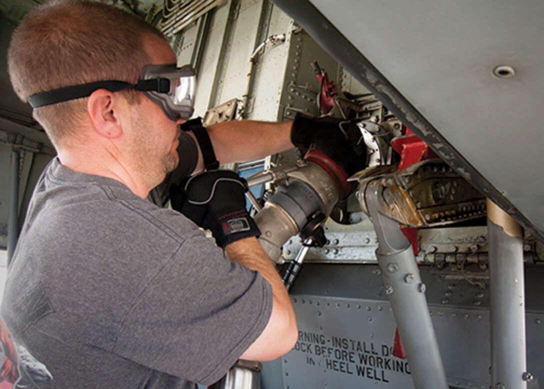 Maintenance worker attaches fuel line to a plane