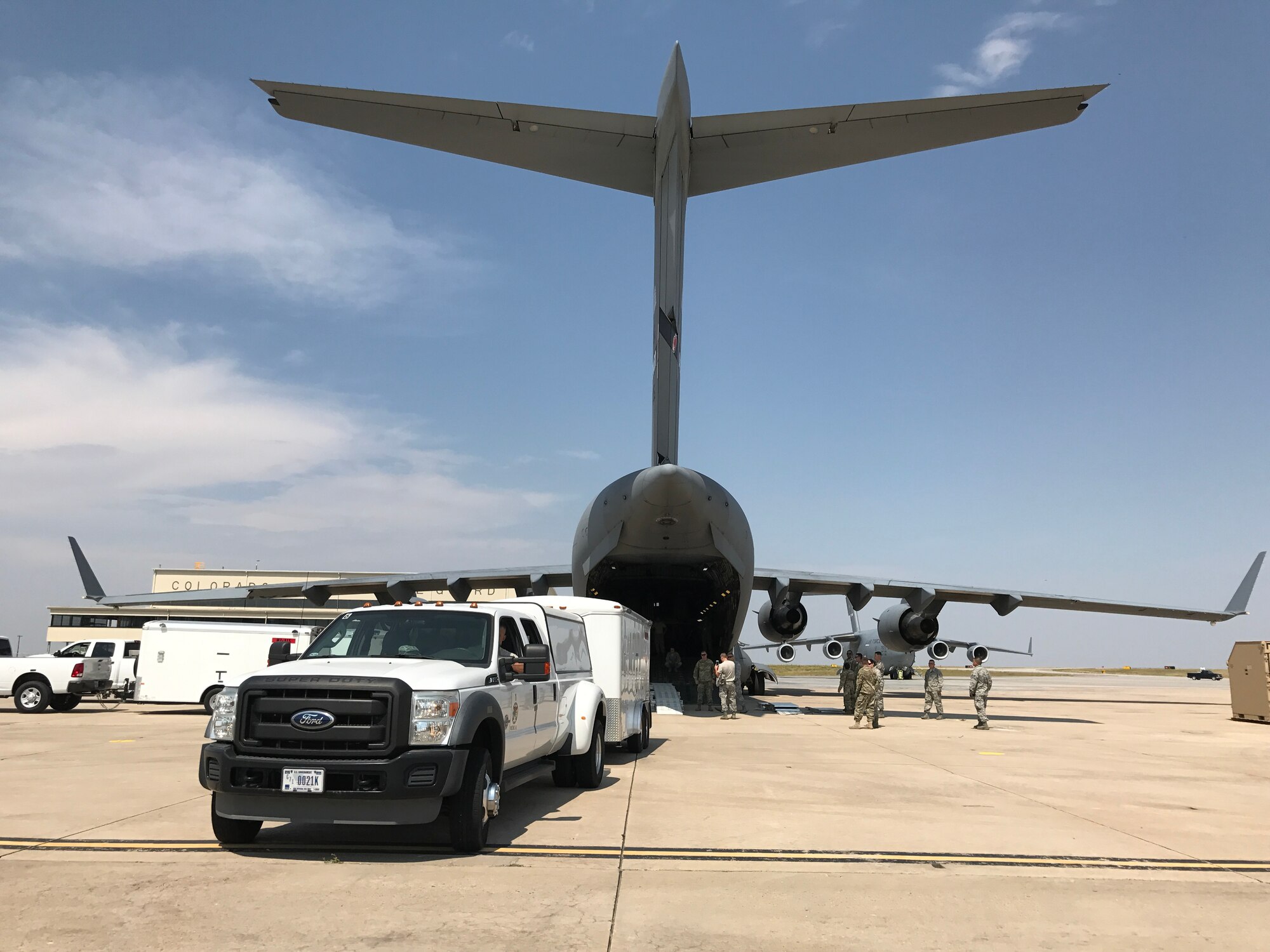 A truck and trailer are backed into a C-17 aircraft