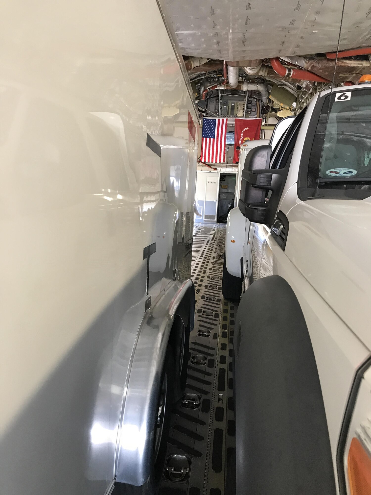 two trucks and trailers driving onto a C-17 aircraft