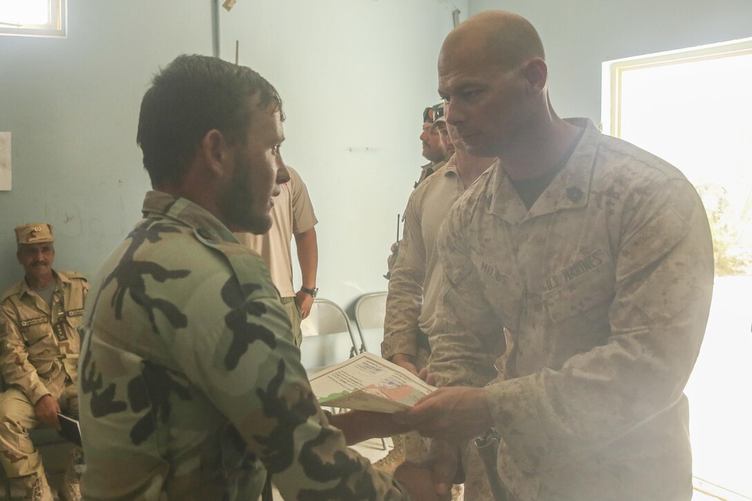 A U.S. Marine advisor with Task Force Southwest hands a certificate of completion to an Afghan National Army soldier with 215th Corps during a graduation ceremony at Camp Shorabak, Afghanistan, Aug. 30, 2017. Advisors with the unit led an eight-week route clearance course with approximately 70 ANA soldiers, enhancing their capabilities to locate and destroy improvised explosive devices and mines, which allows for improved mobility of infantry units and supply chains during operations throughout Helmand province. (U.S. Marine Corps photo by Sgt. Lucas Hopkins)