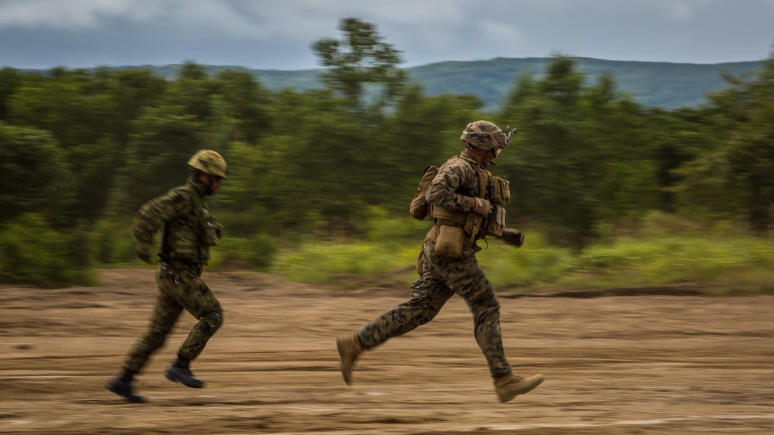 A U.S. Marine and Japan Ground Self-Defense Force member rush out of an MV-22 Osprey at Hokkaido, Japan, August 18, 2017, in support of Northern Viper 2017. This exercise tests the interoperability and bilateral capability of the JGSDF and U.S. Marine Corps forces to work together and provides the opportunity to conduct realistic training in an unfamiliar environment. This combined-joint exercise is held to enhance regional cooperation between participating nations to collectively deter security threats. (U.S. Marine Corps photo by Lance Cpl. Andy Martinez)