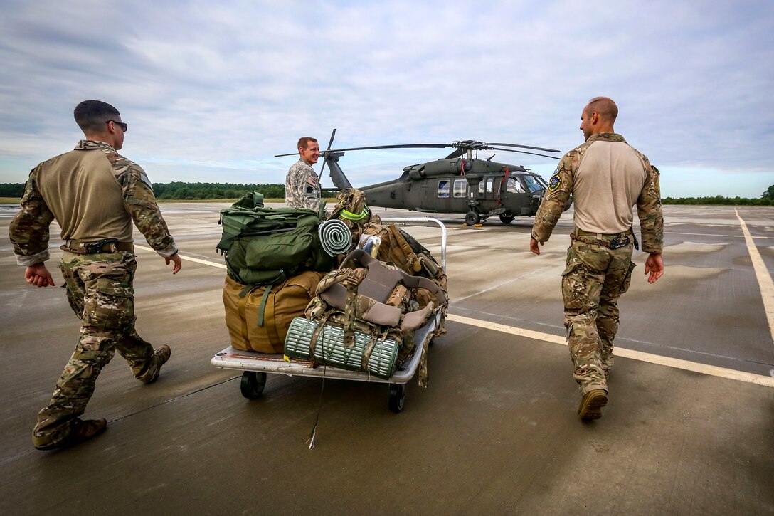 New Jersey Army and Air National Guardsmen take gear to a UH-60 Black Hawk helicopter.