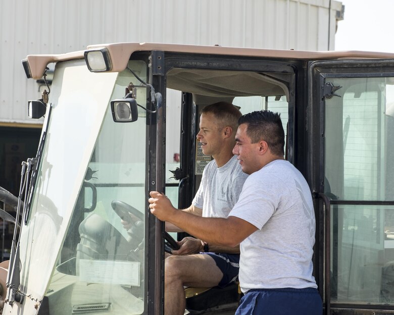 Brig. Gen. Derek C. France, left, 380th Air Expeditionary Wing commander, learns to drive a forklift from Airman 1st Class Cristian Narino Garcia, 380th Expeditionary Force Support Squadron services journeyman, Aug. 31, 2017, at Al Dhafra Air Base, United Arab Emirates.