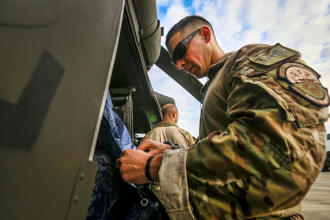Senior Airman Ryan O'Grady secures gear on a UH-60 Black Hawk helicopter.