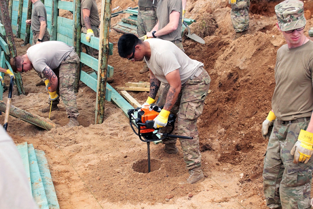 Soldiers dig holes to build a trench.