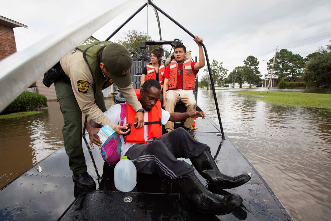 A Border Patrol riverine agent secures a resident in his boat during search and rescue operations