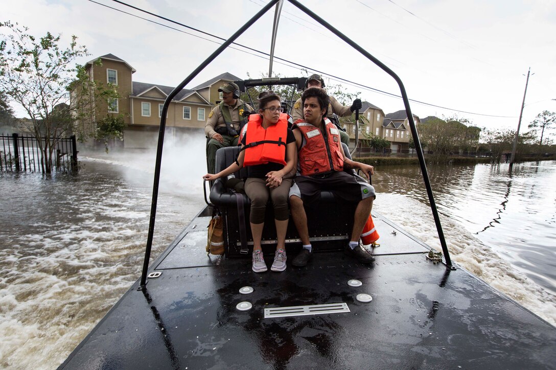 A Border Patrol agent drives an airboat carrying two boys wearing life vests.