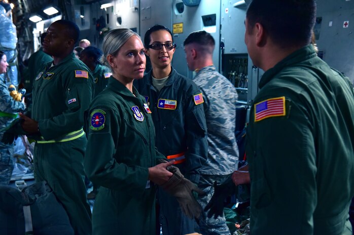 Three Airmen huddle together in an aircraft.