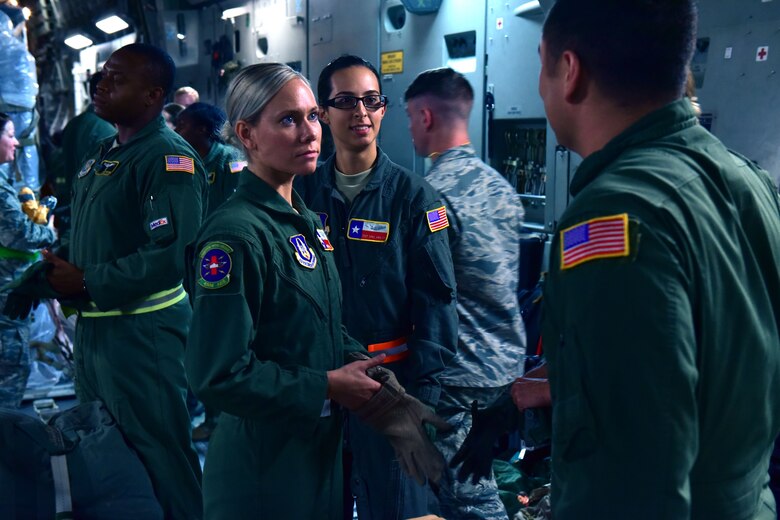Three Airmen huddle together in an aircraft.
