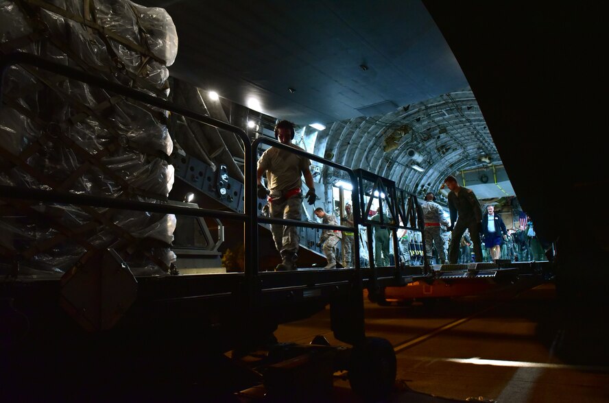 Cargo is loaded onto a C-17 by U.S. Airmen at night.