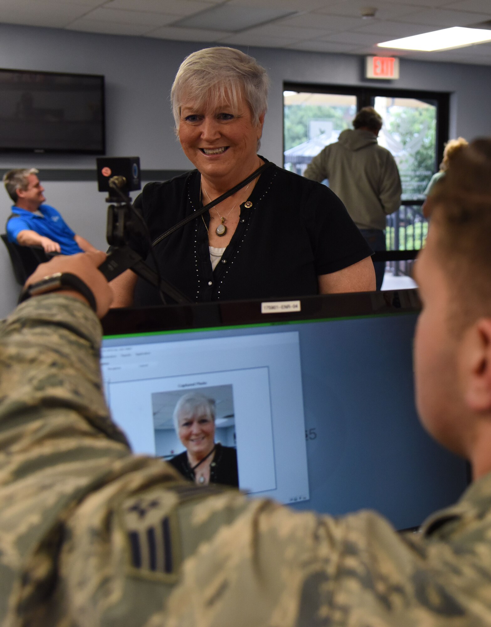 Senior Airman Matias Acuna, 81st Security Forces Squadron visitors center clerk, takes a photo of Nora Moore for her Gold Star Family Member ID card at the visitor center Aug. 29, 2017, on Keesler Air Force Base, Mississippi. As a surviving daughter of a missing in action service member, Moore is allowed to obtain an ID card for recognition and installation access so that she can attend events and access A&FRC referral services. She is Keesler’s first Gold Star Family Member. (U.S. Air Force photo by Kemberly Groue)