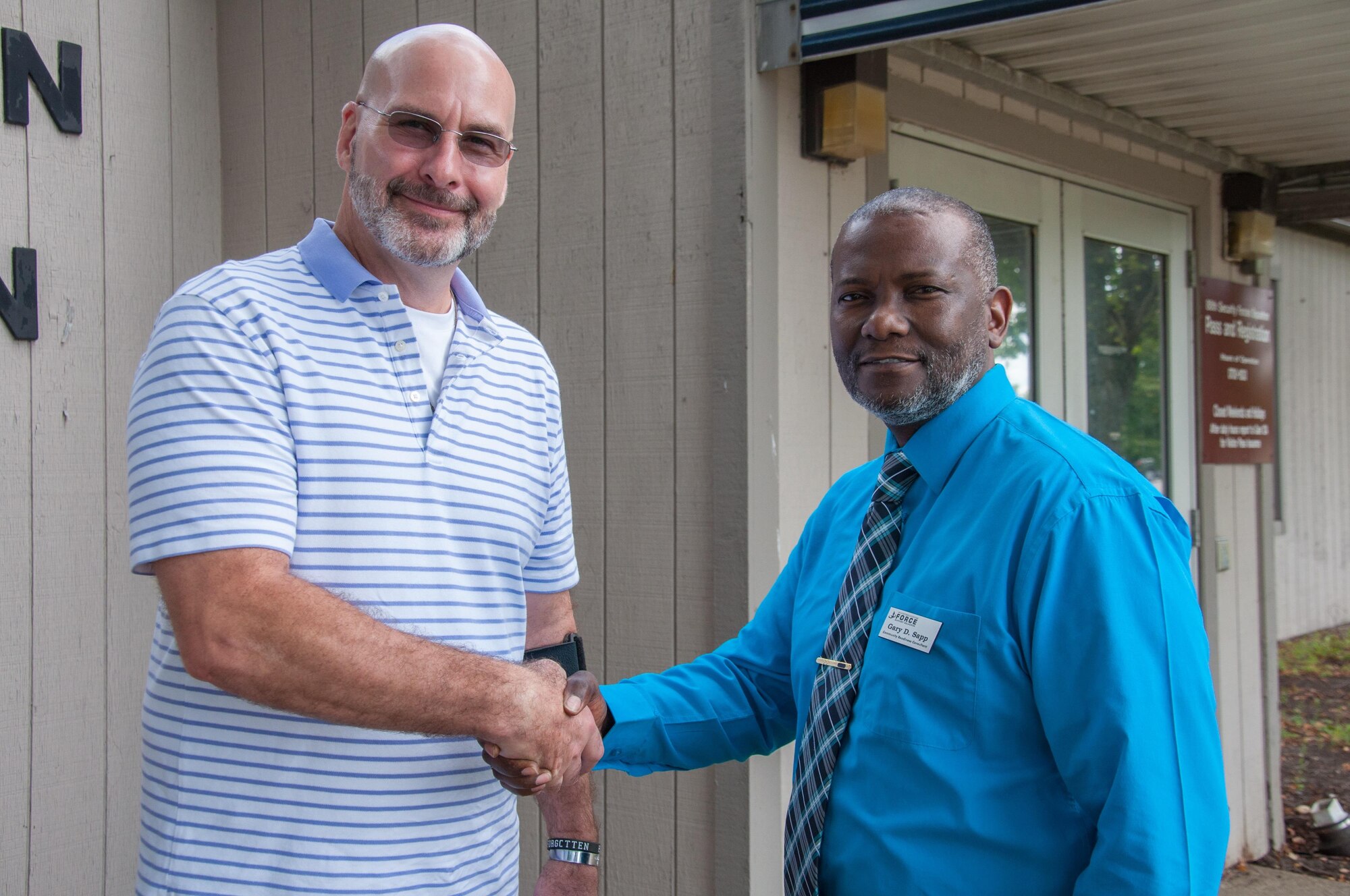 WRIGHT-PATTERSON AIR FORCE BASE, Ohio – Joseph Bryan Stuart (left) shakes hands with Garry Sapp, Airman and Family Readiness Center Community Readiness consultant, after obtaining the first Gold Star Family Member ID card issued at Wright-Patterson August 25. The base is one of five Air Force installations testing the program to define and refine procedures. (U.S. Air Force photo/John Harrington)