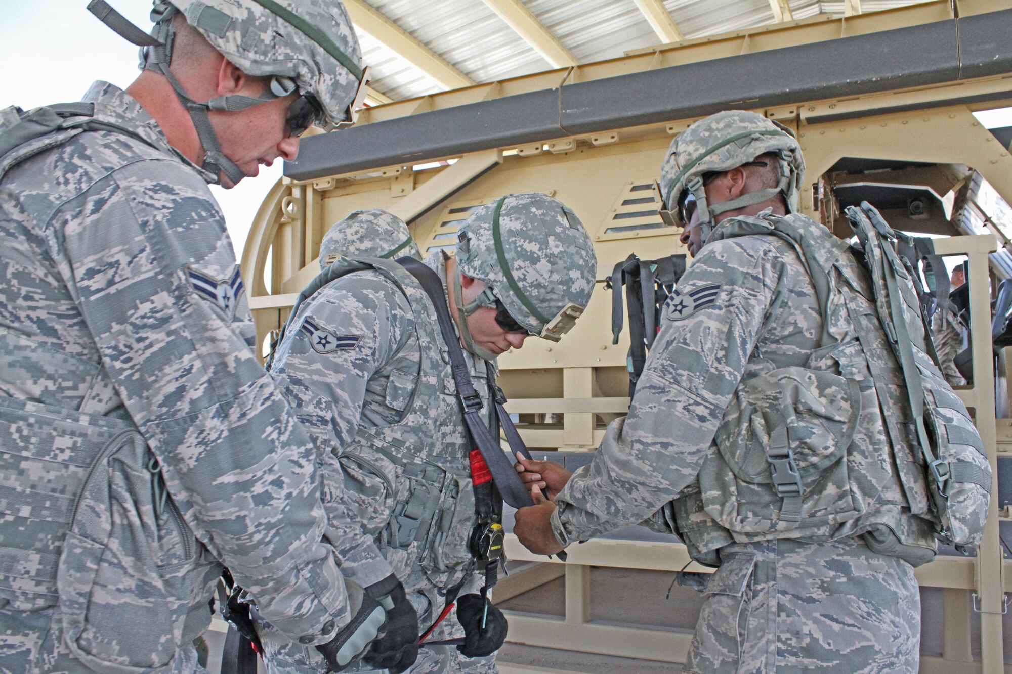 Security forces students help a gunner don his harness before entering a vehicle rollover simulator during the basic security course at the Air Force Security Forces Center Desert Defender Ground Combat Readiness Training Center, Fort Bliss, Texas.