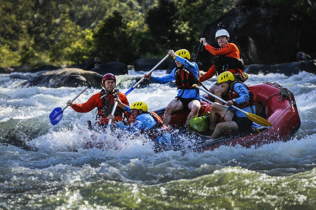 Troops paddle through raging waters aboard an inflatable raft.