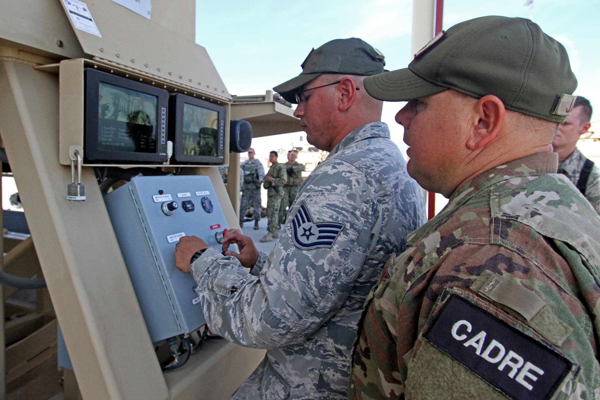 Cadre member Staff Sgt. Steven Milanez rotates a vehicle rollover simulator loaded with security forces students while fellow cadre member Tech. Sgt. Stacy James looks on.