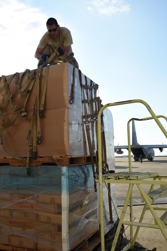 Air Force Tech. Sgt. Lucas Ortega (top), 73rd Aerial Port Squadron cargo supervisor, adjusts webbing on a pallet used to secure American Red Cross supplies before their transport August 29, 2017, at Naval Air Station Fort Worth Joint Reserve Base, Texas, in support of Hurricane Harvey relief efforts. There were 90,000 lbs. of supplies, included blankets and cots, sent as part of the Defense Support of Civil Authority. Department of Defense provides medium and heavy lift rotary wing assets, along with ground transportation, to move personnel, commodities and equipment within Texas. (U.S. Air Force photo by Ms. Julie Briden-Garcia)