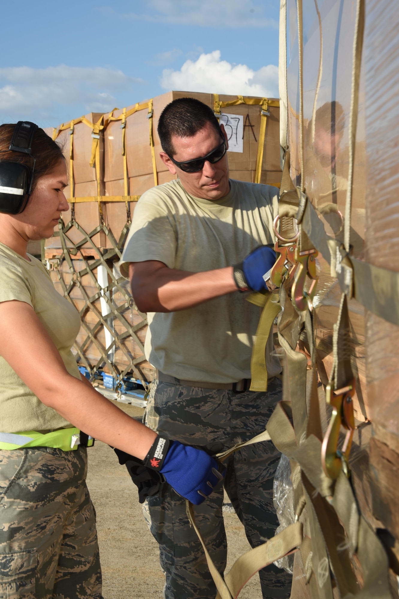 (left to right) Air Force Master Sgt. Viviana Molina, 73rd Aerial Port Squadron air transportation, and Tech. Sgt. Lucas Ortego, 73 APS cargo supervisor, secure webbing straps on 90,000 lbs. of American Red Cross supplies August 29, 2017, at Naval Air Station Fort Worth Joint Reserve Base, Texas, in support of Hurricane Harvey relief efforts. Supplies included blankets and cots and were transported as part of the Defense Support of Civil Authority. Department of Defense provides medium and heavy lift rotary wing assets, along with ground transportation, to move personnel, commodities and equipment within Texas. (U.S. Air Force photo by Ms. Julie Briden-Garcia)