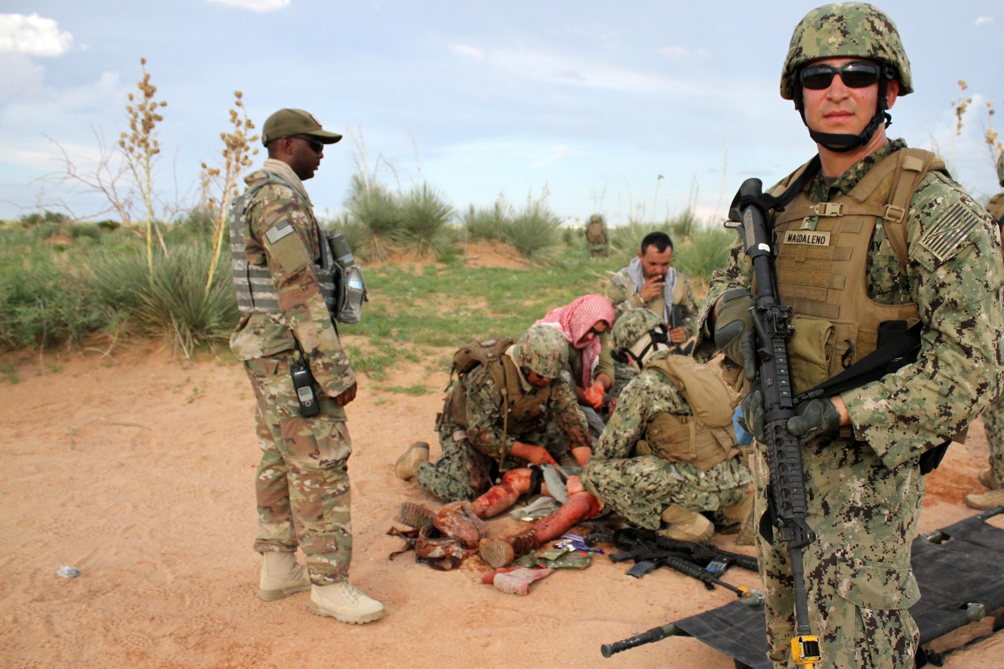 A U.S. Navy masters-at-arms treat and comfort a simulated improvised explosive device victim while other team members keep watch for other threats.