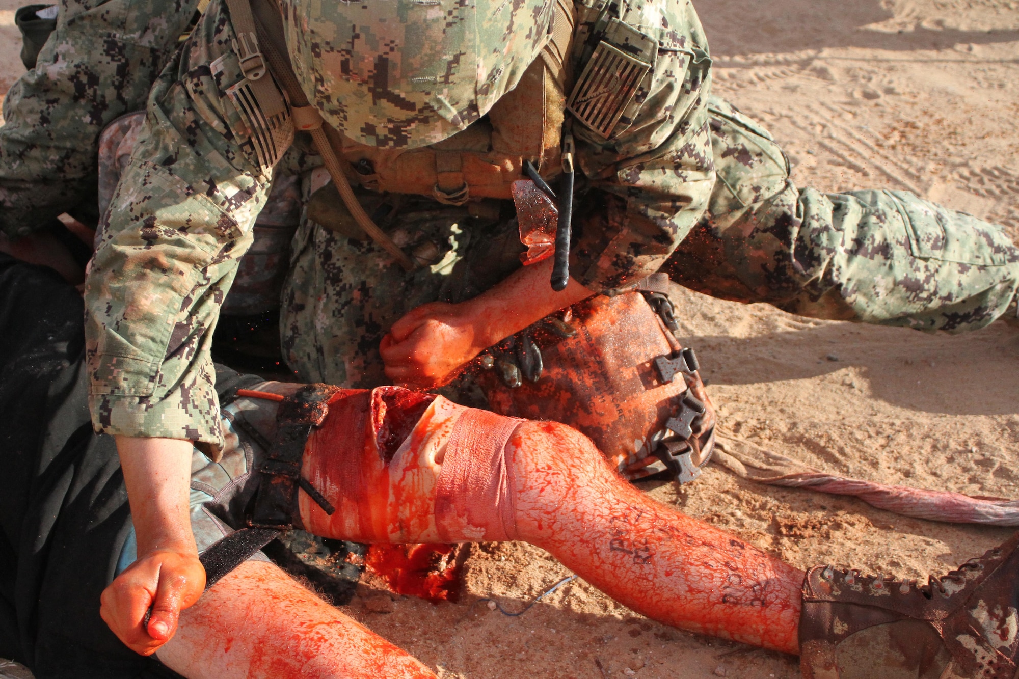 A U.S. Navy master-at-arms applies a tourniquet to a simulated improvised explosive device victim.