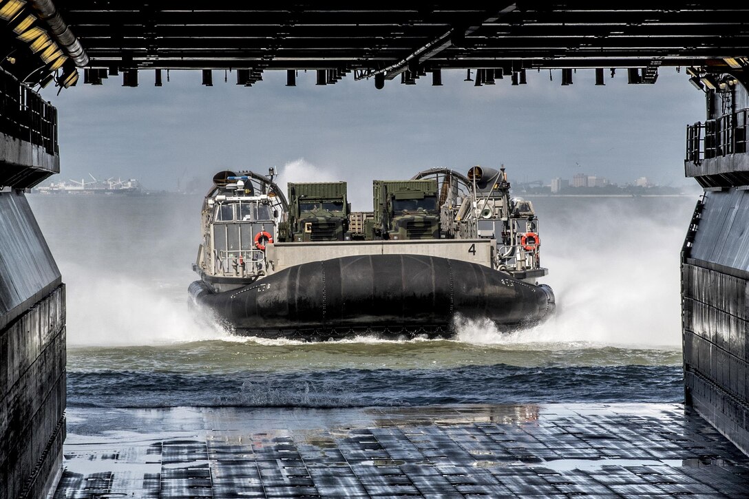 An air-cushioned landing craft creates a wake as it enters a well deck.