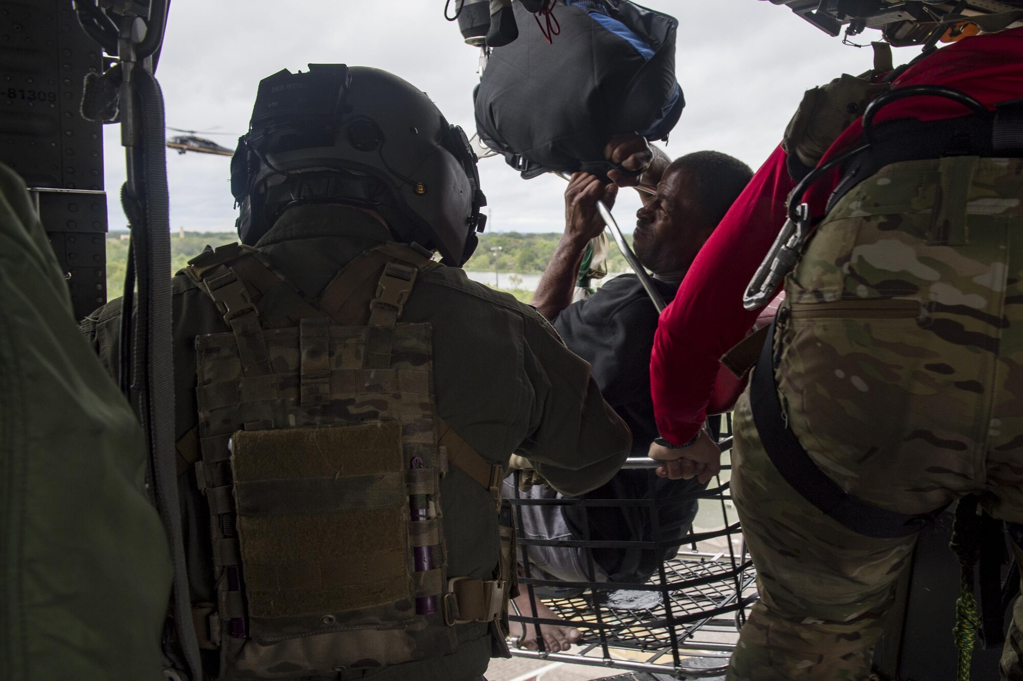 A special missions aviator from the 41st Rescue Squadron, and a pararescueman from the 38th Rescue Squadron, secures a basket carrying an evacuee, Aug. 30, 2017, over a residence in the Houston, Texas area.