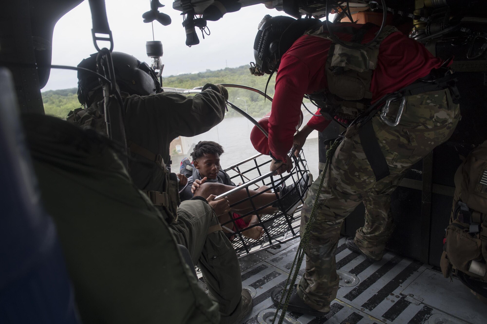 A special missions aviator from the 41st Rescue Squadron, and a pararescueman from the 38th Rescue Squadron, secures a basket carrying evacuees, Aug. 30, 2017, over a residence in the Houston, Texas area.